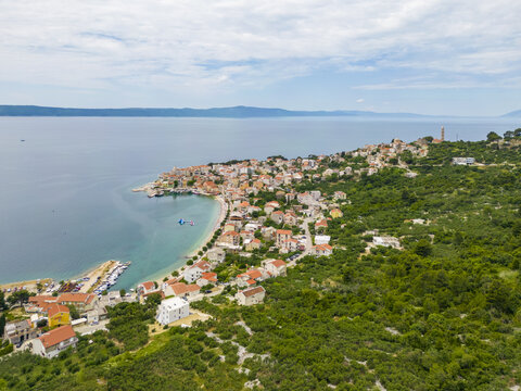 Aerial view of terracotta rooftops cascade down to meet the turquoise Adriatic sea, embraced by verdant hillsides, Igrane, Split-Dalmatia County, Croatia.