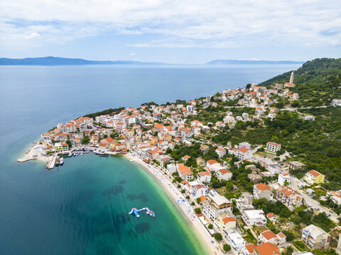 Aerial view of the coastal town's terracotta rooftops cascading down to the turquoise waters of the Adriatic, a vibrant contrast against the green hills, Igrane, Split-Dalmatia County, Croatia.