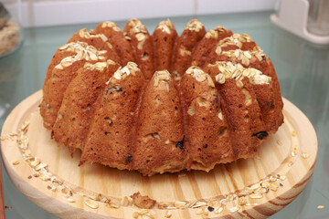 Homemade oatmeal bread with nuts and raisins baked in a Bundt Pan displayed on a wooden board 