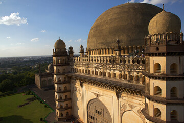 Aerial view of the magnificent Gol Gumbaz, its towering dome casting a golden glow against the azure sky, Bijapur, Karnataka, India.