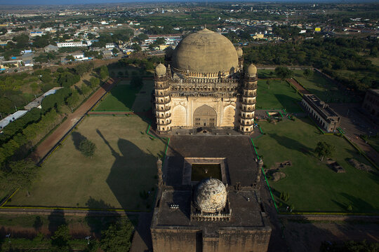 Aerial view of the majestic Gol Gumbaz standing tall amidst lush greenery, a testament to architectural grandeur, Bijapur, Karnataka, India.