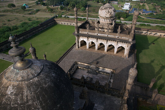 Aerial view of the Ibrahim Roza complex with its weathered domes and intricate archways amidst a verdant lawn, Vijayapura, Karnataka, India.