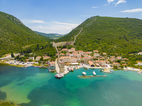 Aerial view of the tranquil turquoise waters embracing the historic town and ancient walls snaking up the lush green hillsides, Mali Ston, Dubrovnik-Neretva County, Croatia.