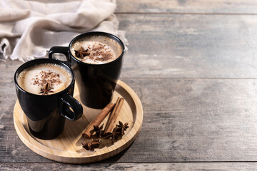Chai Latte in Black Mug with Spices( star anise and cinnamon) on wooden table. Copy space