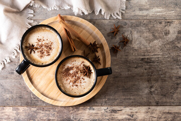 Chai Latte in Black Mug with Spices( star anise and cinnamon) on wooden table. Top view. Copy space