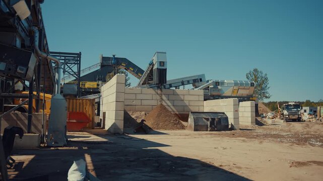 Dirt sortiment falling at an outdoor construction waste sorting facility on a sunny day