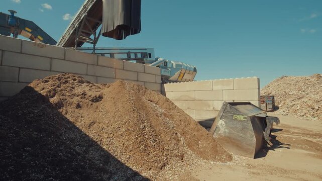 Dirt sortiment falling at an outdoor construction waste sorting facility on a sunny day