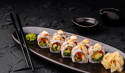 Sushi rolls with fresh vegetables served on elegant black plate