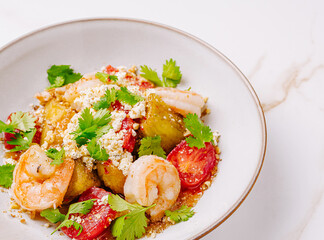 Shrimp and vegetable dish served in a bowl with fresh herbs and toppings
