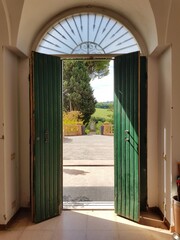 View through an antique wooden door onto fields in Tuscany