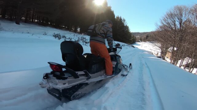 Rescuer man snowmobiling through scenic winter forest trail on clear day
