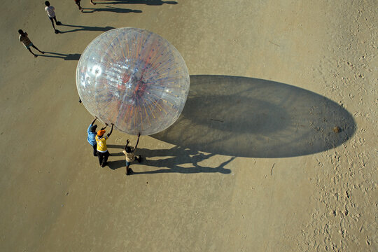 Mangaluru, India - 17 January 2010: Aerial view of a giant inflatable transparent ball casting a dramatic shadow on the golden sands of the beach.