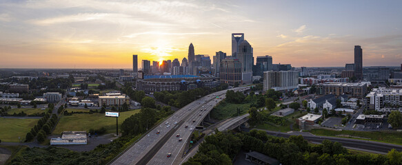Charlotte, United States - 30 July 2025: Aerial view of the city skyline glowing at sunset, with Bank of America Stadium and busy highways below.