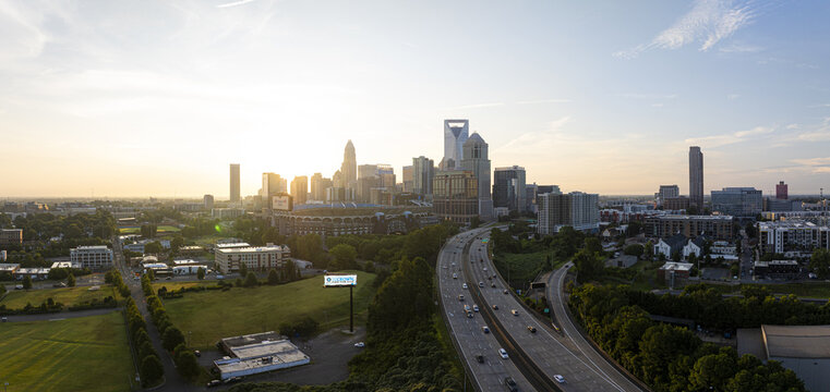 Charlotte, United States - 30 July 2025: Aerial view of the gleaming cityscape with Bank of America Corporate Center and Truist Field, cutting through lush greenery and bustling highways.