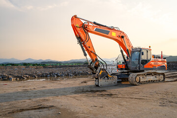 A powerful excavator rests at a construction site during golden hour, surrounded by dirt and rocky terrain, showcasing industrial strength, heavy machinery, and ongoing earthmoving work.