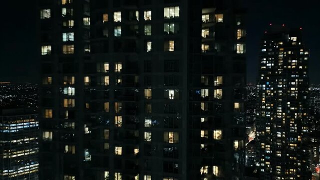A drone pulls back from a person in a high-rise window showing urban loneliness and isolation