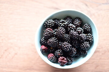 Top view of a bowl filled with fresh blackberries. The vibrant dark purple berries create a visually appealing and healthy snack option, perfect for summer, natural food, and fruit themes.