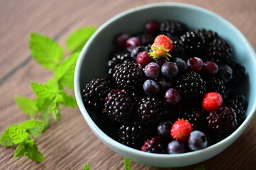 Close-up macro view of a bowl with fresh seasonal fruits — blackberries, blueberries, and mint. A vibrant and healthy mix of summer berries, perfect for fresh eating, healthy lifestyle, and food photo