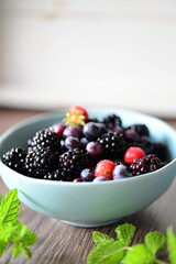 Close-up macro view of a bowl with fresh seasonal fruits — blackberries, blueberries, and mint. A vibrant and healthy mix of summer berries, perfect for fresh eating, healthy lifestyle, and food photo