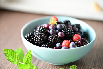 Close-up macro view of a bowl with fresh seasonal fruits — blackberries, blueberries, and mint. A vibrant and healthy mix of summer berries, perfect for fresh eating, healthy lifestyle, and food photo