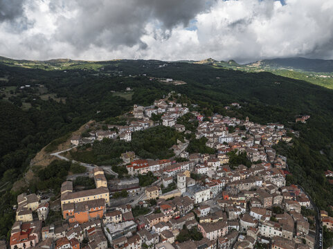Aerial view of the town with terracotta rooftops nestled against verdant hills, under a dramatic sky, Morcone, Benevento, Italy.