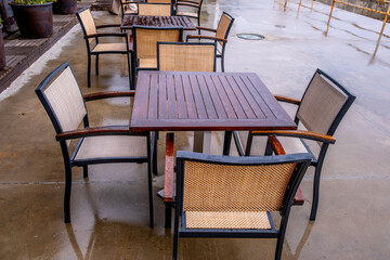 A table with chairs in the park after the rain.