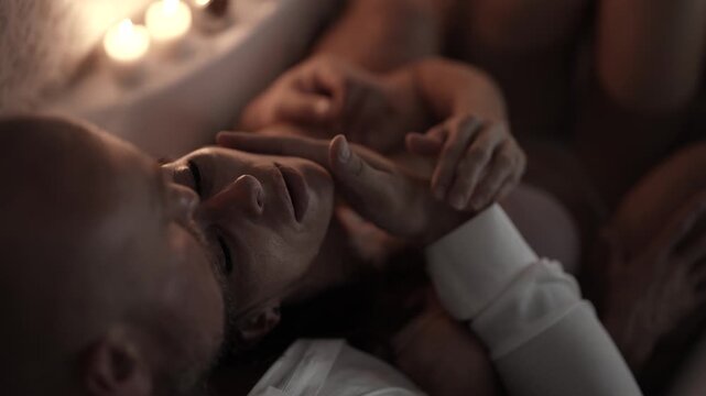 A man's hand gently touches a woman's lips, her eyes are closed, an intimate and touching moment.