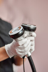 Cosmetologist's hands holding a cavitation device in their hands
