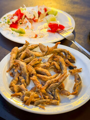 Fried Fish and Partially Eaten Salad. Close-up of crispy fried fish with partially eaten salad on table under warm sunset light. Concept of casual dining, comfort food, relaxed evening meal