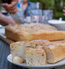 Focaccia, Italian bread, decorated with roasted garlic and fresh rosemary. The recipe calls for lots of olive oil and a slow rise.