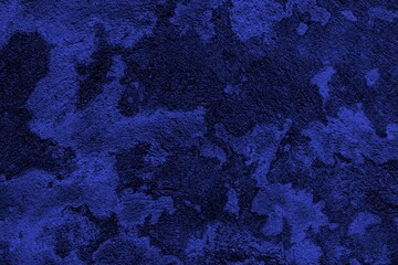 Close-up view of a blue textured wall showing rough patterns and intricate shadow details, offering a visually appealing background texture for versatile creative uses.