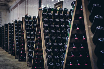 Bottles of sparkling wine during stage of production method called riddling in famous winery in...