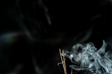 Dancing incense smoke with light in the dark.