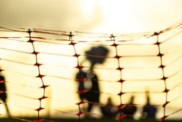 Unidentified people blurred in silhouette behind a plastic fence during a dramatic sunset. Winter...