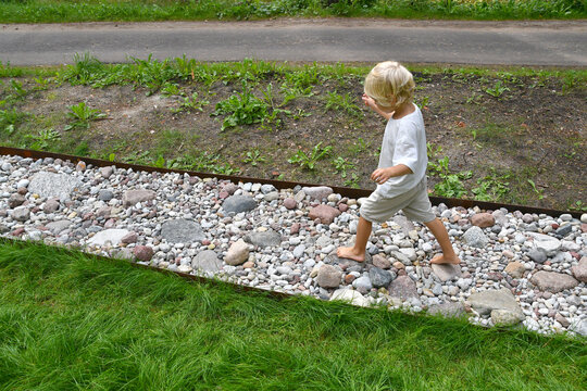 Barefoot boy walking on a sensory trail through a sunny pine forest in summer