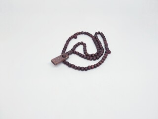 A close-up shot of wooden prayer beads necklace with a rectangular pendant, lying on a white surface. Ideal for religious and spiritual concepts.