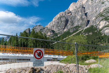 Verbotsschild an Baustellenabsperrung vor Bergkulisse