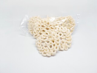 Close-up of a package of kerupuk udang, Indonesian shrimp crackers, a popular crispy snack. The white crackers are in a clear plastic bag, with a white background.
