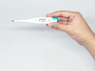 A hand holding a digital thermometer, displaying a temperature reading. The image is set against a...