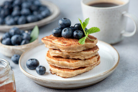 Healthy vegetarian oat pancakes with blueberries on a plate, served with coffee