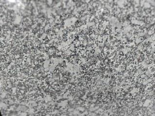 High-resolution close-up image of a polished gray granite surface, showcasing its natural speckled pattern and texture. Ideal for use in backgrounds, design projects, architecture, and construction