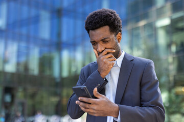 A businessman wearing a suit checks his smartphone outside a office building, displaying worry and focus. The image highlights urban life, technology integration, and professional challenges.