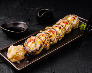 Delicious sushi rolls served on a black plate with wasabi and sauce
