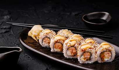 Sushi rolls served on a wooden platter with wasabi and chopsticks nearby