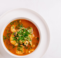 Spicy seafood soup served in a white bowl on a clean surface