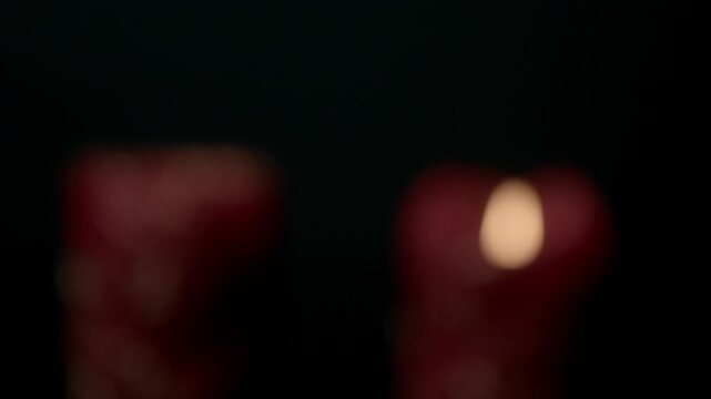 Detailed view of a burning red candle with intricate decorative designs against a dark background, creating a warm and intimate atmosphere. Perfect for relaxation or meditation visuals.