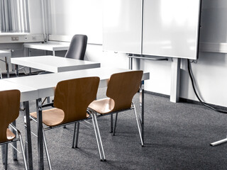 Empty classroom with brown chairs and white tables, gray wallpaper