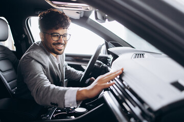 Obraz premium Business man sitting in new car in a car showroom