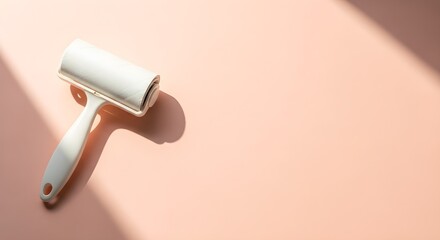 White lint roller with handle casting a shadow on a light pink background with diagonal light streaks