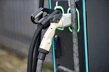 Electric Vehicle Charging Station With Dual Connectors: Close-Up Of Modern EV Power Supply Cables And Sockets With Green LED Outlines On Black Panel In Urban Setting